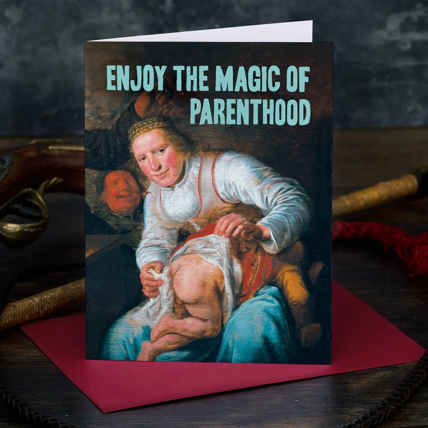 Greeting card with vintage-style illustration of a woman holding a child, text 'Enjoy the Magic of Parenthood', on a dark background.