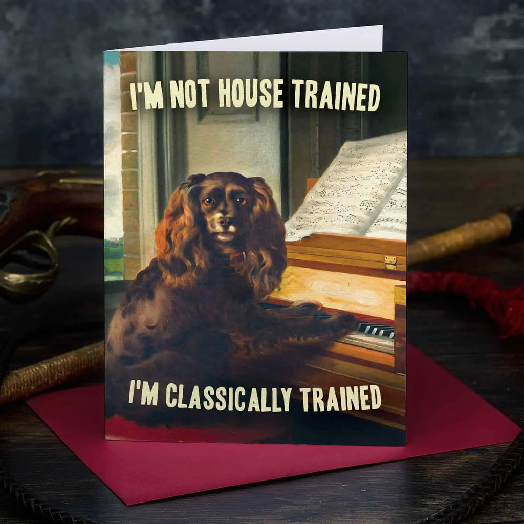 Card with a dog on a piano, text 'I'm not house trained, I'm classically trained', on a dark background.