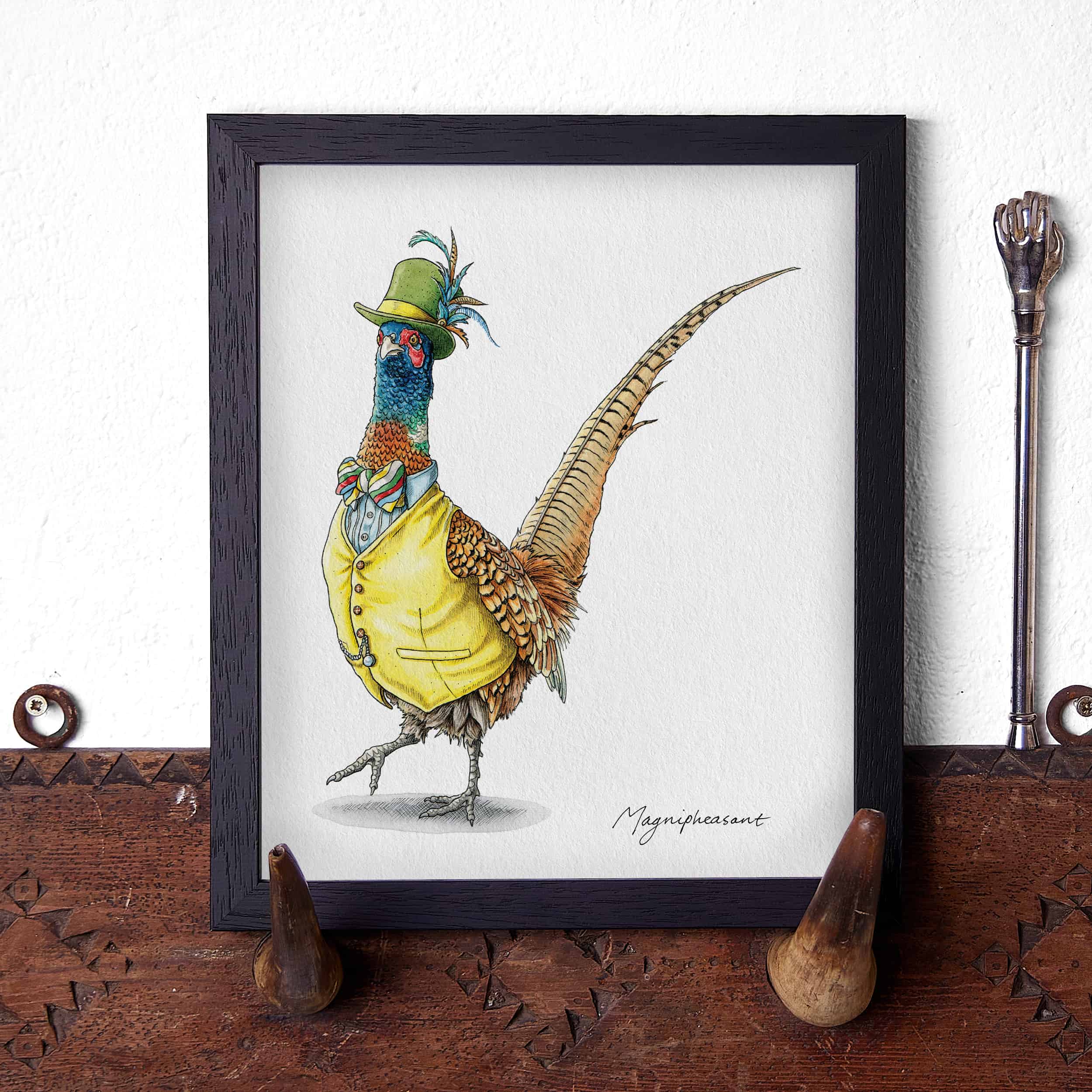 Artwork of a pheasant wearing a yellow jacket and green hat on a wooden surface.