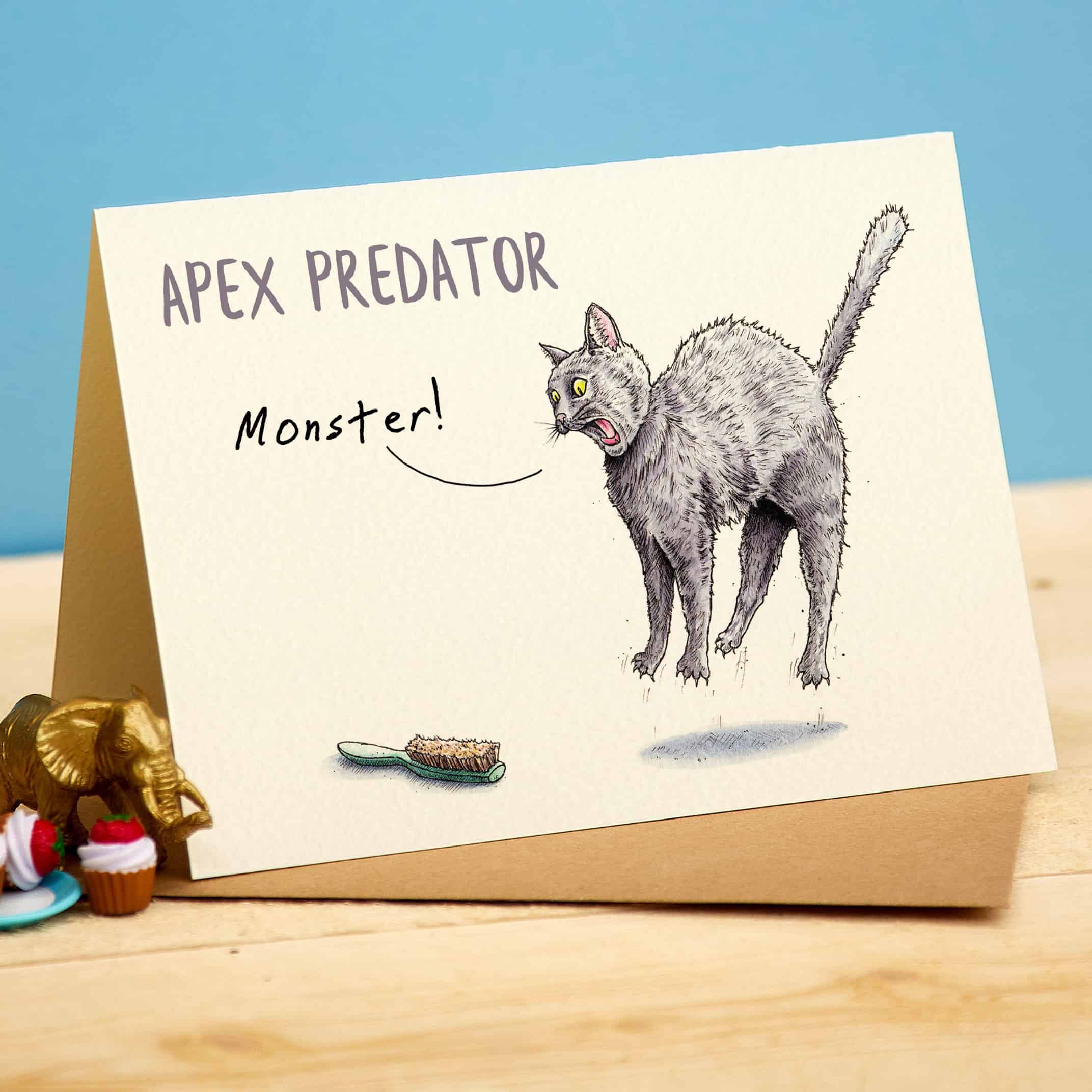 Card with a cat illustration labeled 'Apex Predator Monster' on a wooden surface.