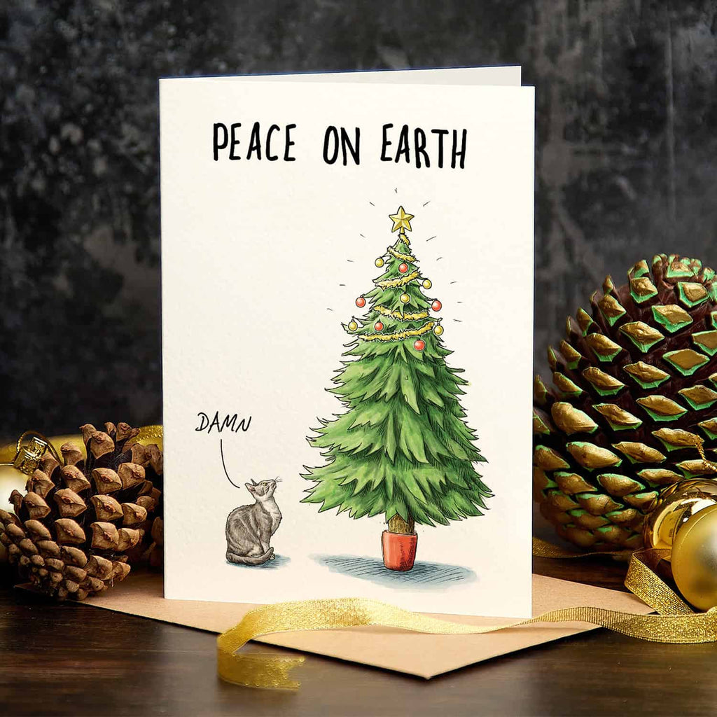Christmas card with a decorated tree and cat, surrounded by pine cones and gold ribbons.