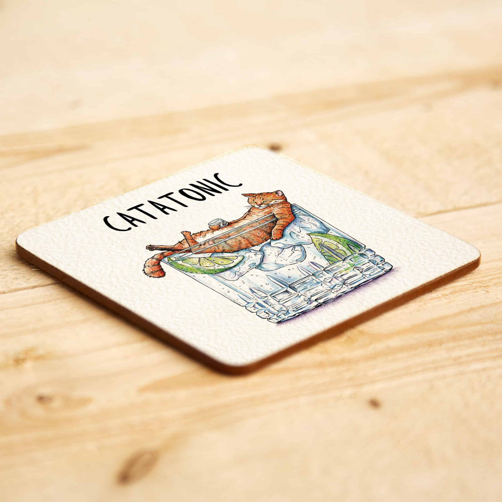 Coaster with a cat illustration and 'CATATONIC' text on a wooden surface