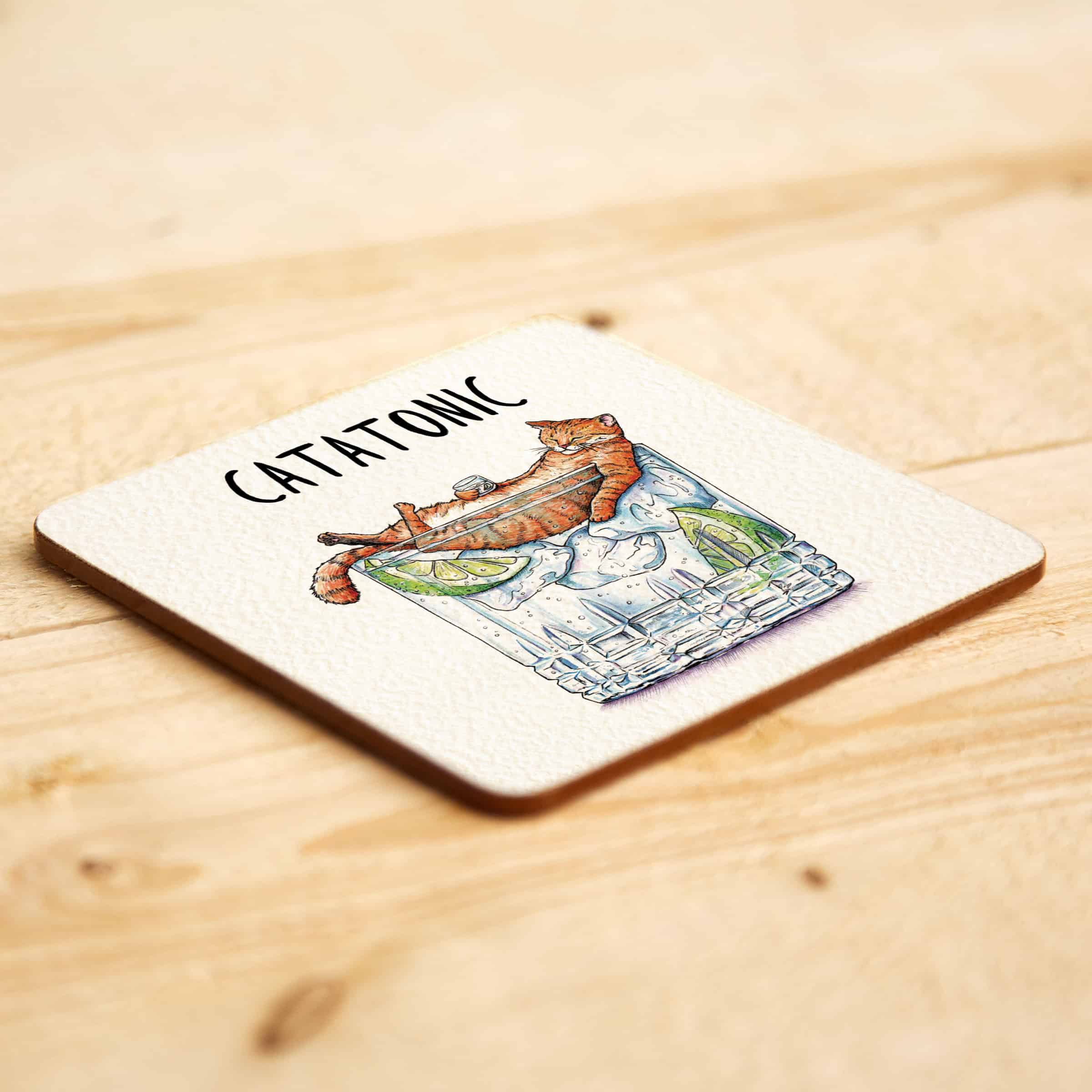 Coaster with a cat illustration and 'CATATONIC' text on a wooden surface