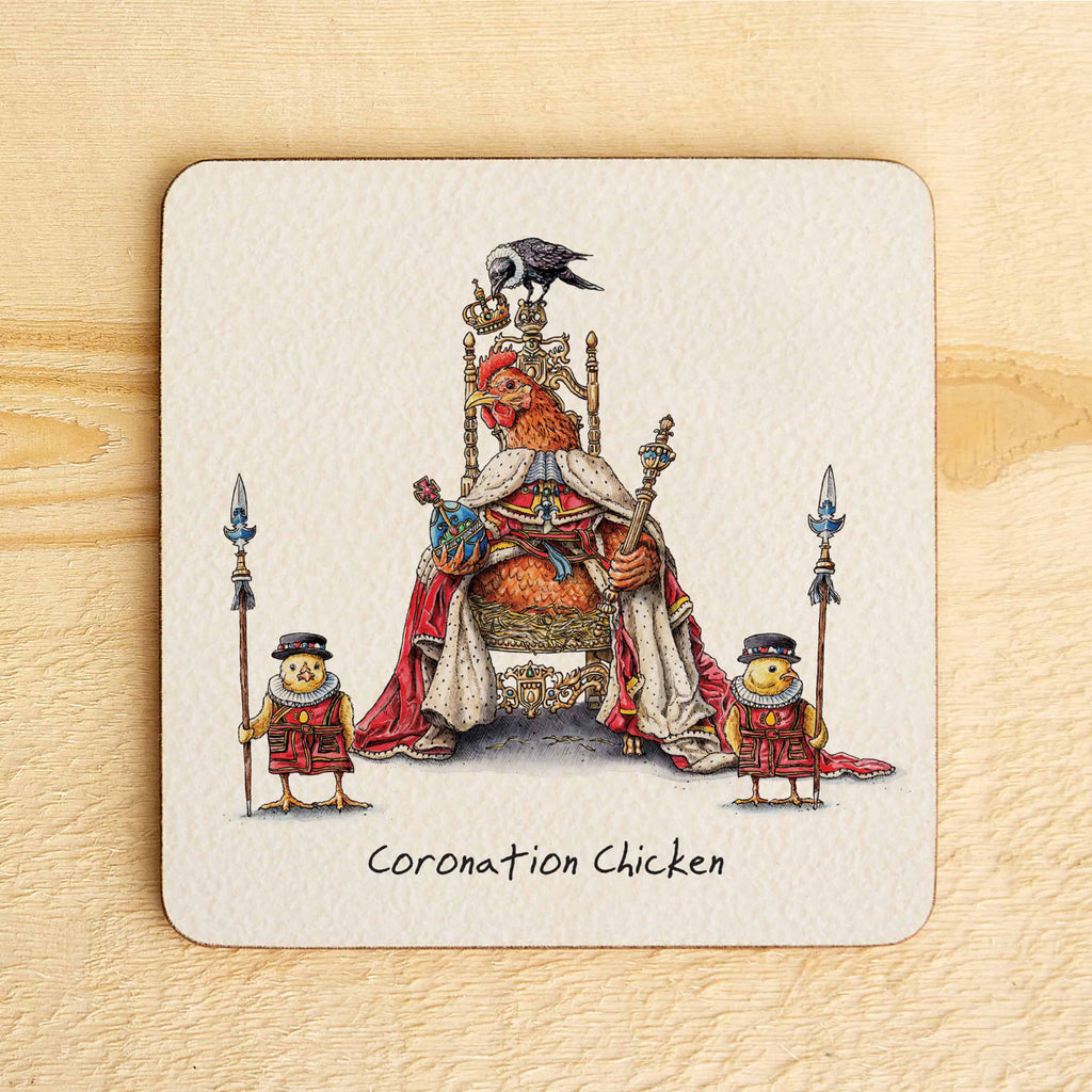 Coaster with illustration of a chicken on a throne, surrounded by two smaller chickens, on a wooden surface.