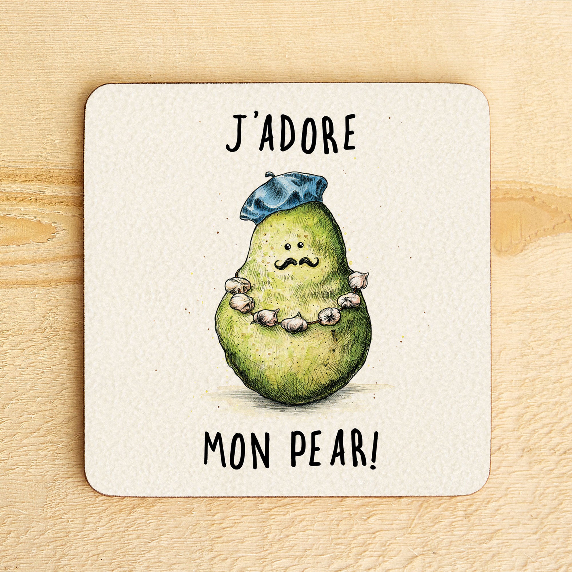 Coaster with a pear illustration wearing a hat and necklace, text 'J'adore mon pear!' on a wooden surface.