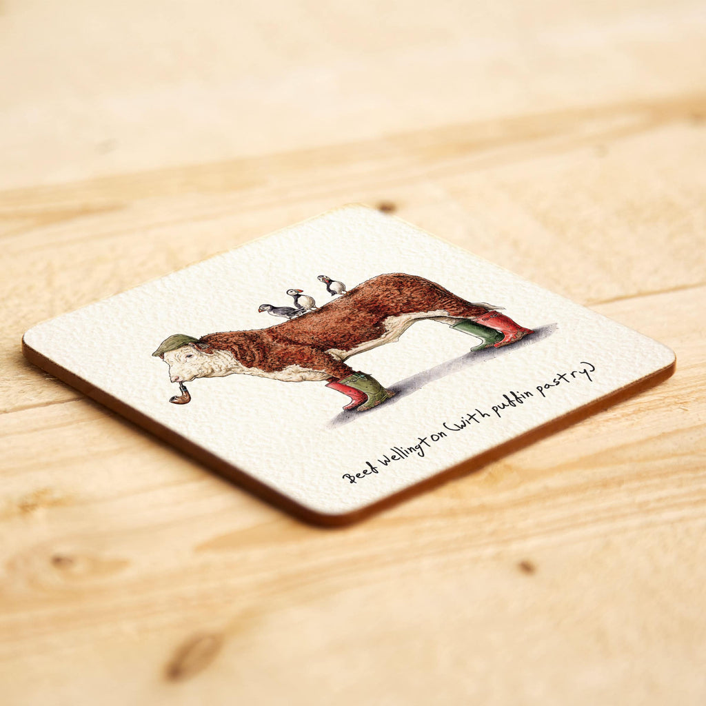 Coaster with a printed design of a cow with funny caption a wooden surface