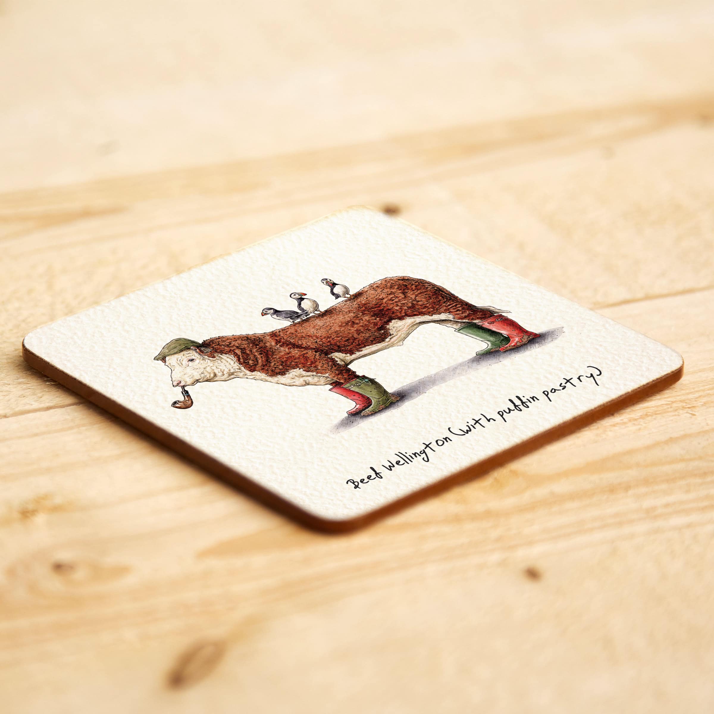 Coaster with a printed design of a cow with funny caption a wooden surface