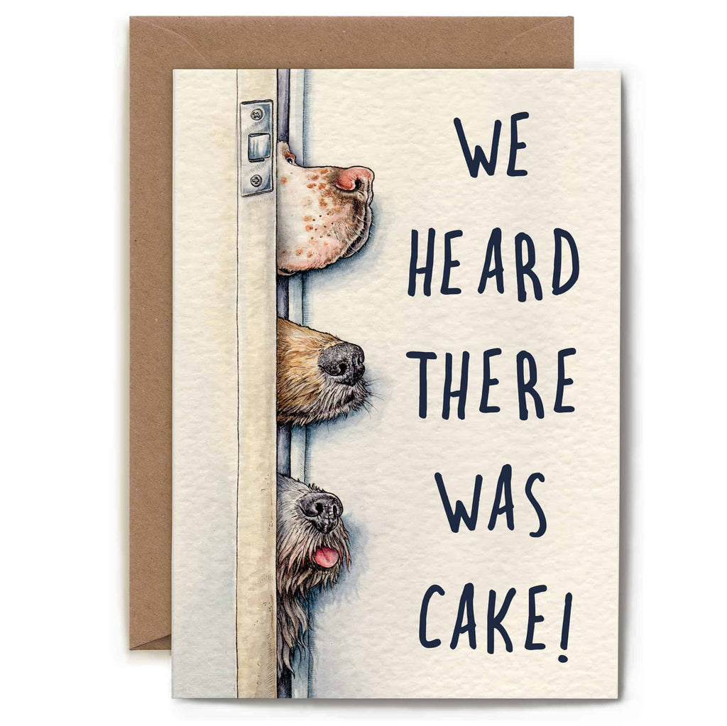 Greeting card with illustration of dogs peeking around a door and text 'We heard there was cake!'.