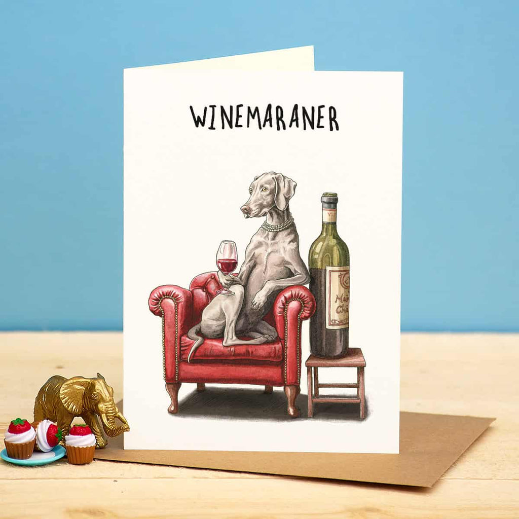 Greeting card with a dog sitting on a red armchair with a wine bottle and glass, labeled 'WINEMARANER'.