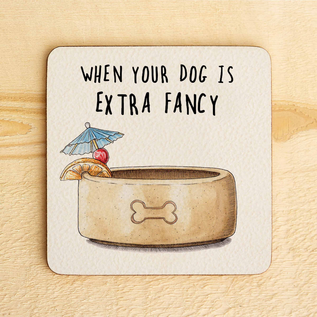 Coaster with a dog bowl illustration and text 'When your dog is extra fancy' on a wooden surface.