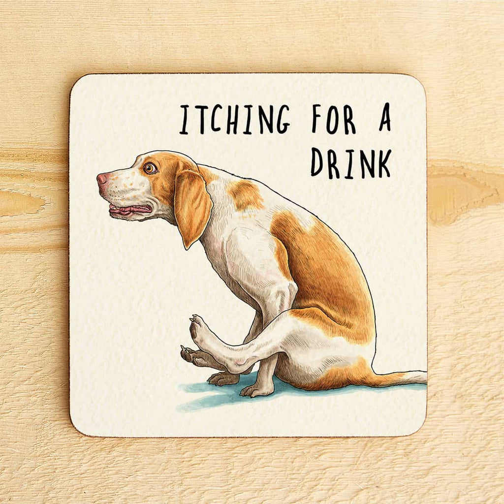 Coaster with a dog illustration and text 'Itching for a Drink' on a wooden surface