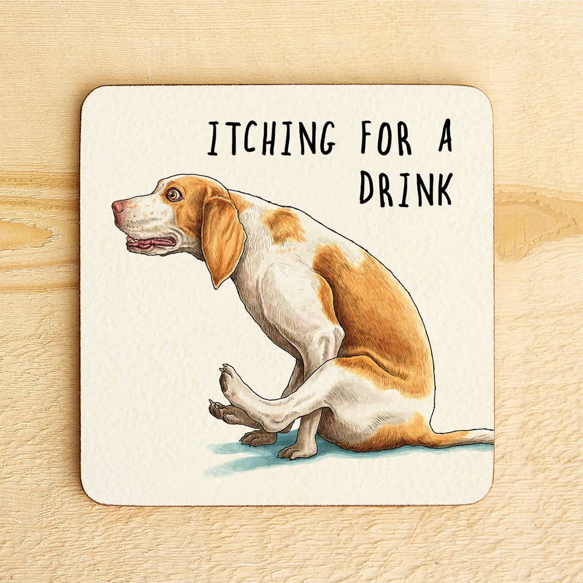 Coaster with a dog illustration and text 'Itching for a Drink' on a wooden surface