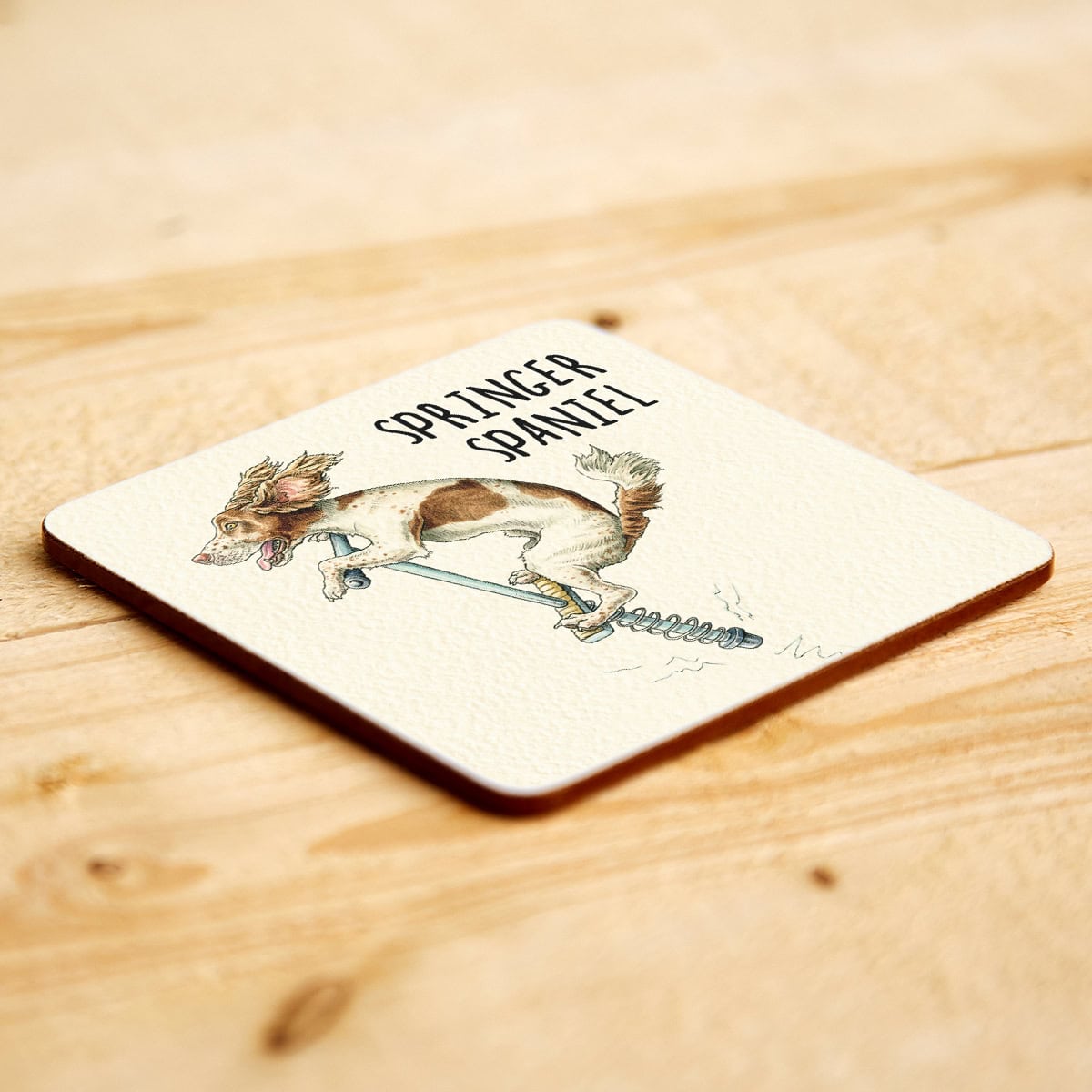 Coaster with a Springer Spaniel illustration and text on a wooden surface