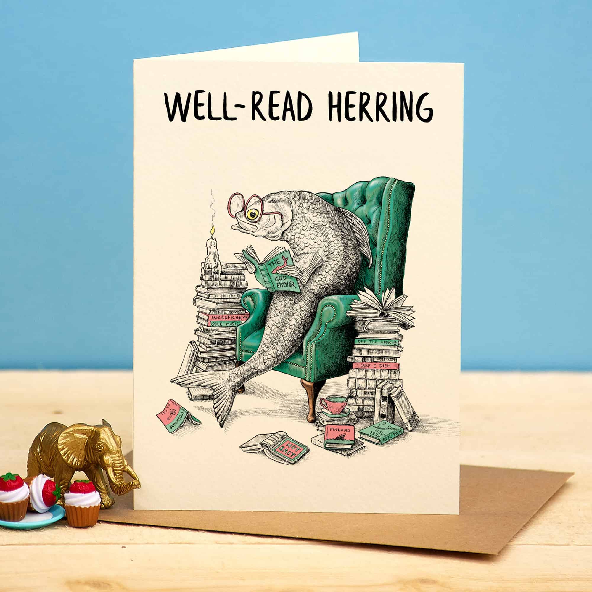 Card with a fish reading a book titled 'Well-Read Herring' on a blue background