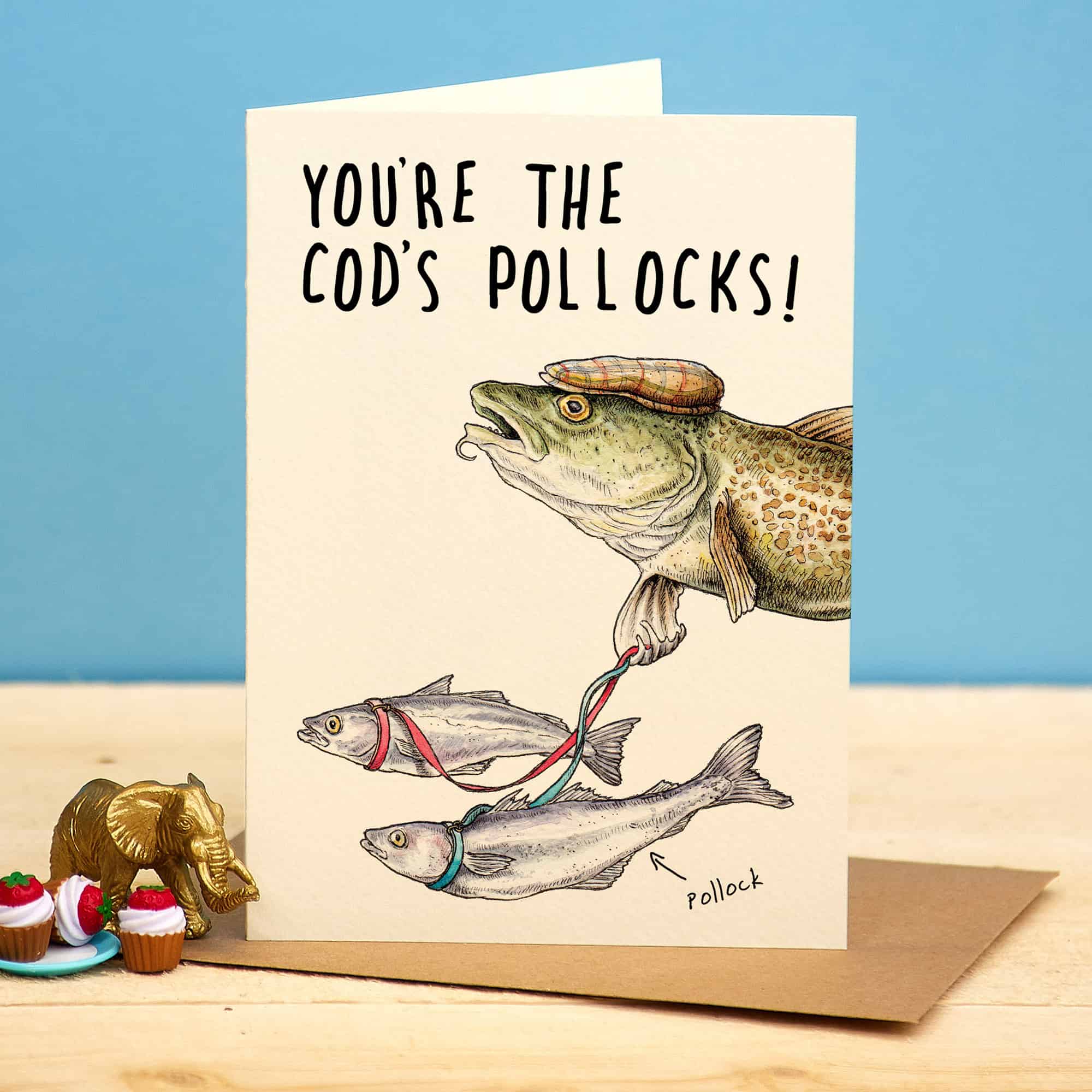 Card with fish illustration and humorous text on a wooden surface with a blue background