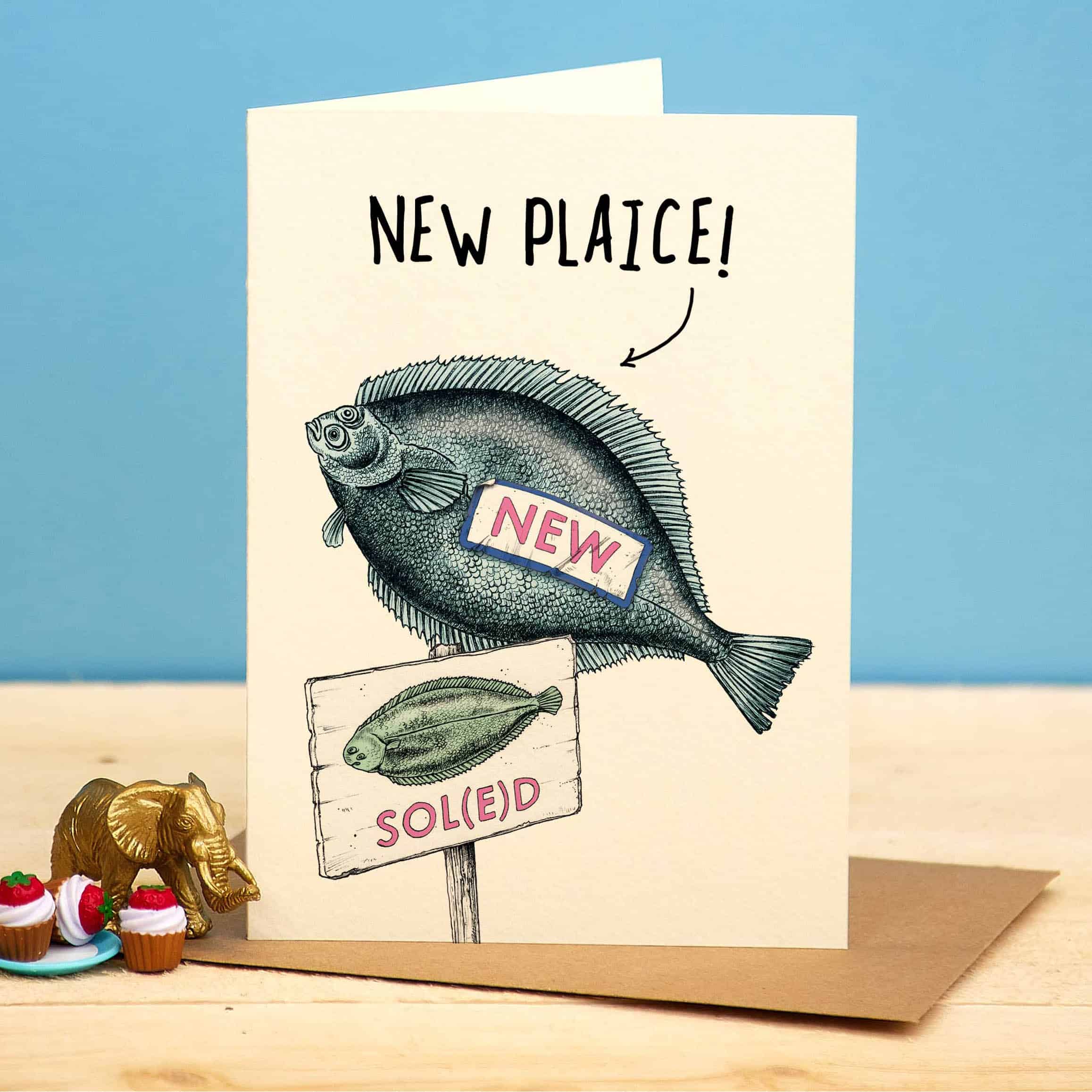 Greeting card with fish illustration and text on a wooden surface with decorative items.