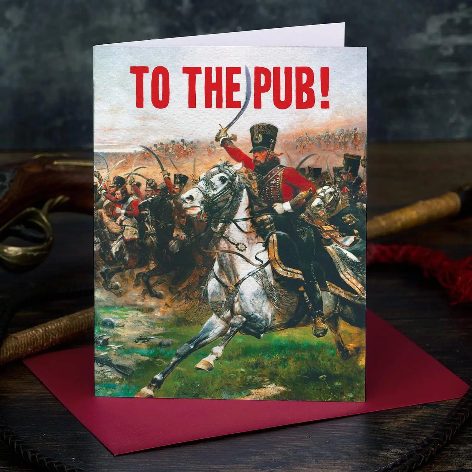 Greeting card with historical scene of a man on horseback and text 'To the Pub!' on a dark background.