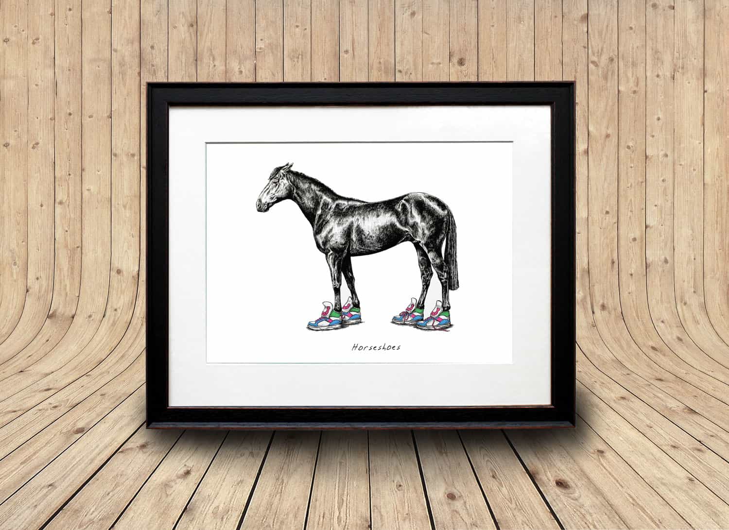Print of a horse wearing bright coloured trainers displayed in a black frame 