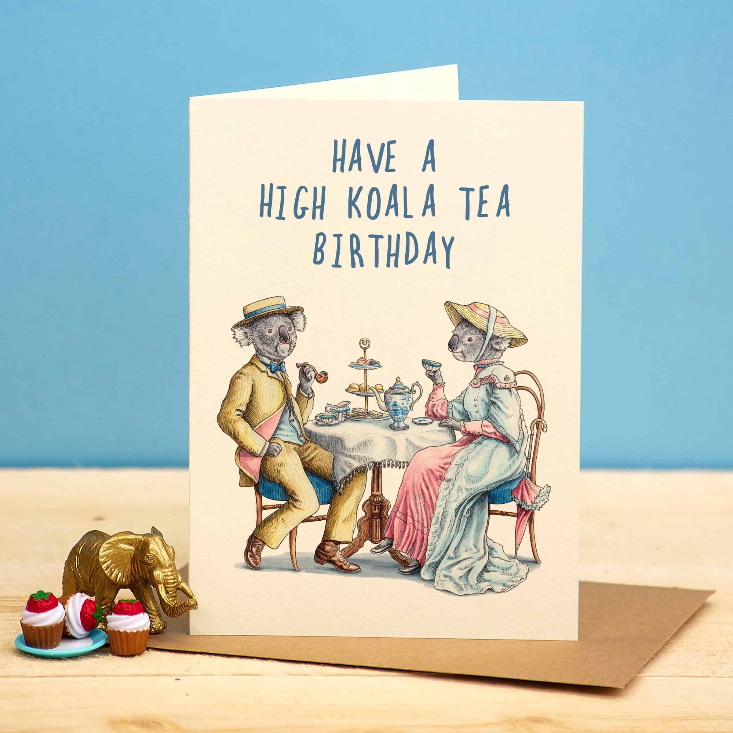 Greeting card with koala illustration and 'Have a High Koala Tea Birthday' text on a blue background.