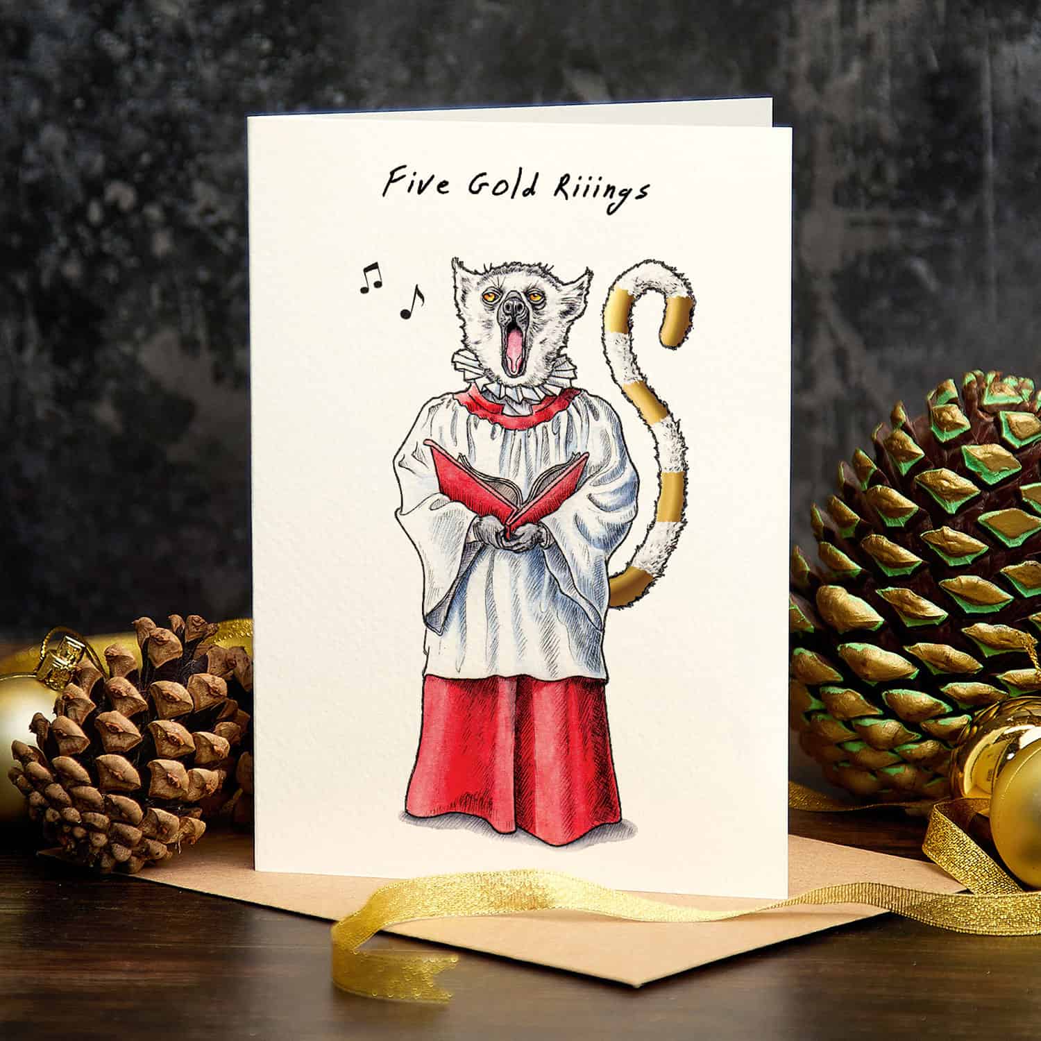 Greeting card with a cat in a choir outfit and 'Five Gold Rings' text, surrounded by decorative elements.