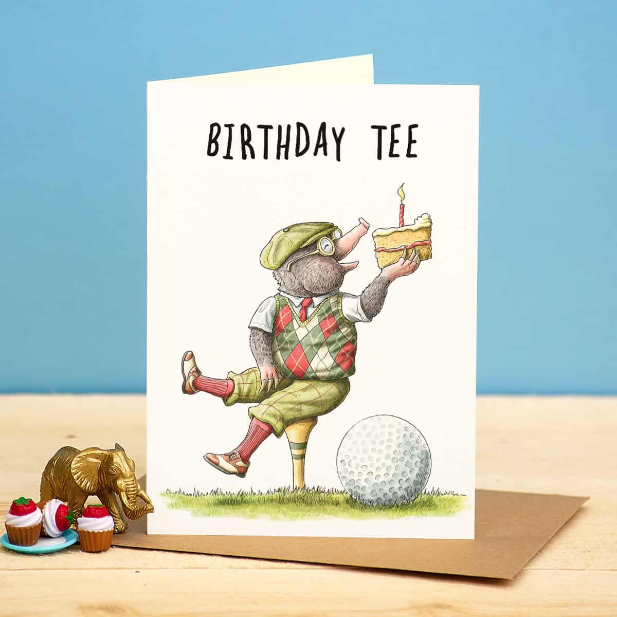 Birthday card with a cartoon character mole holding a cake, standing on a golf ball, with text 'Birthday Tee' on a blue background.