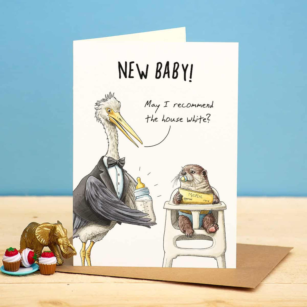 Greeting card with illustrations of a pelican and an otter, featuring text 'New Baby! May I recommend the house white?' on a blue background.