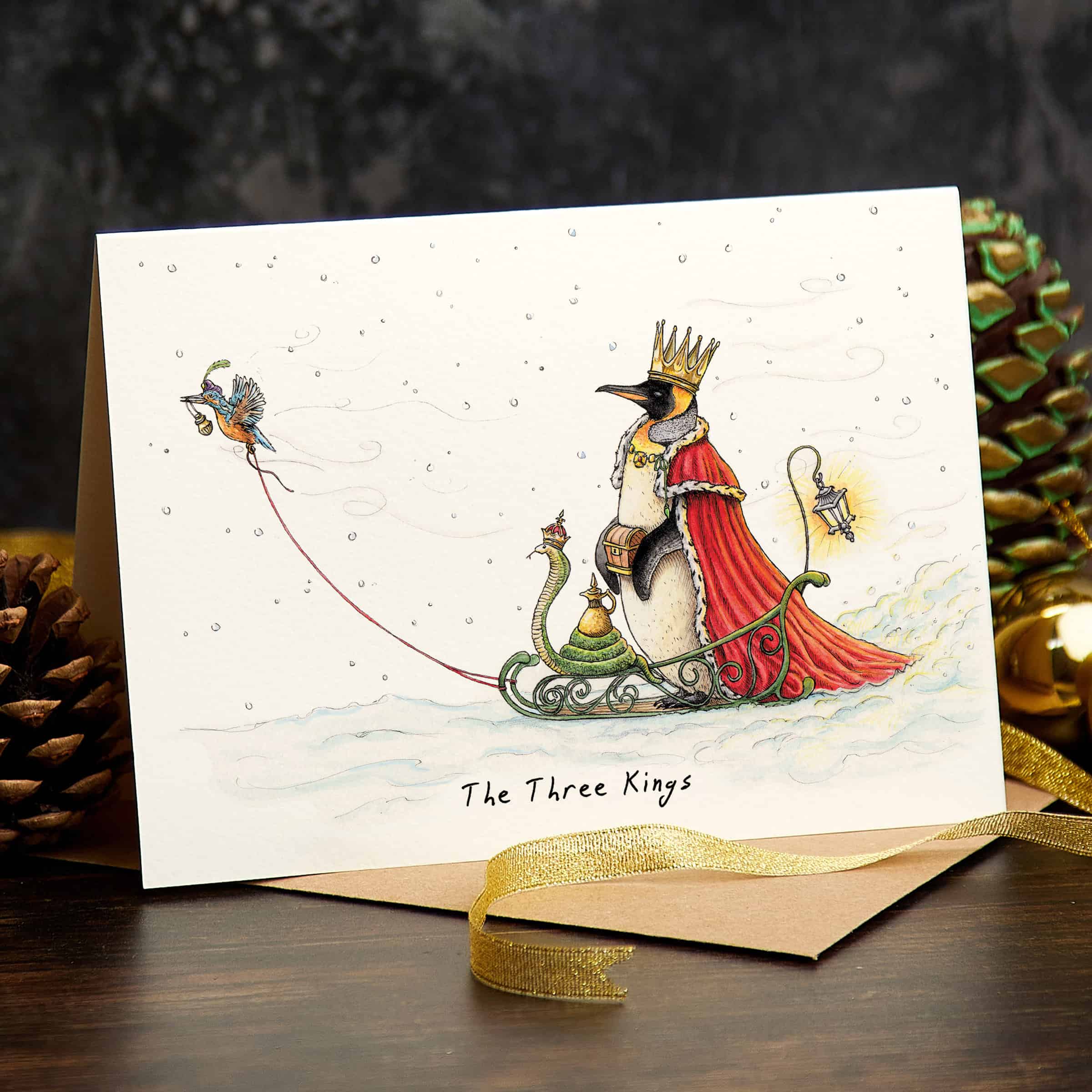 Greeting card with penguin illustration and 'The Three Kings' text, surrounded by decorative elements.