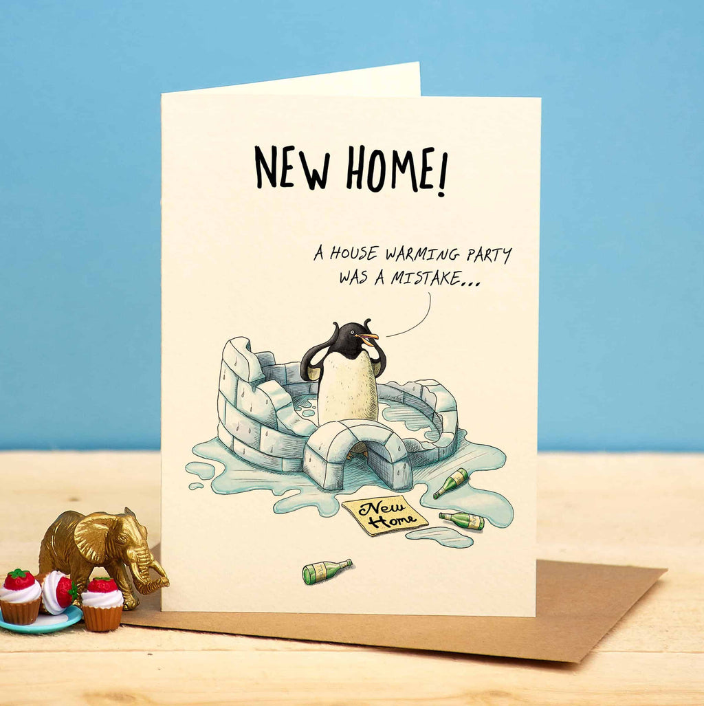 Greeting card with penguin illustration and text about a housewarming party mistake on a blue and beige background.
