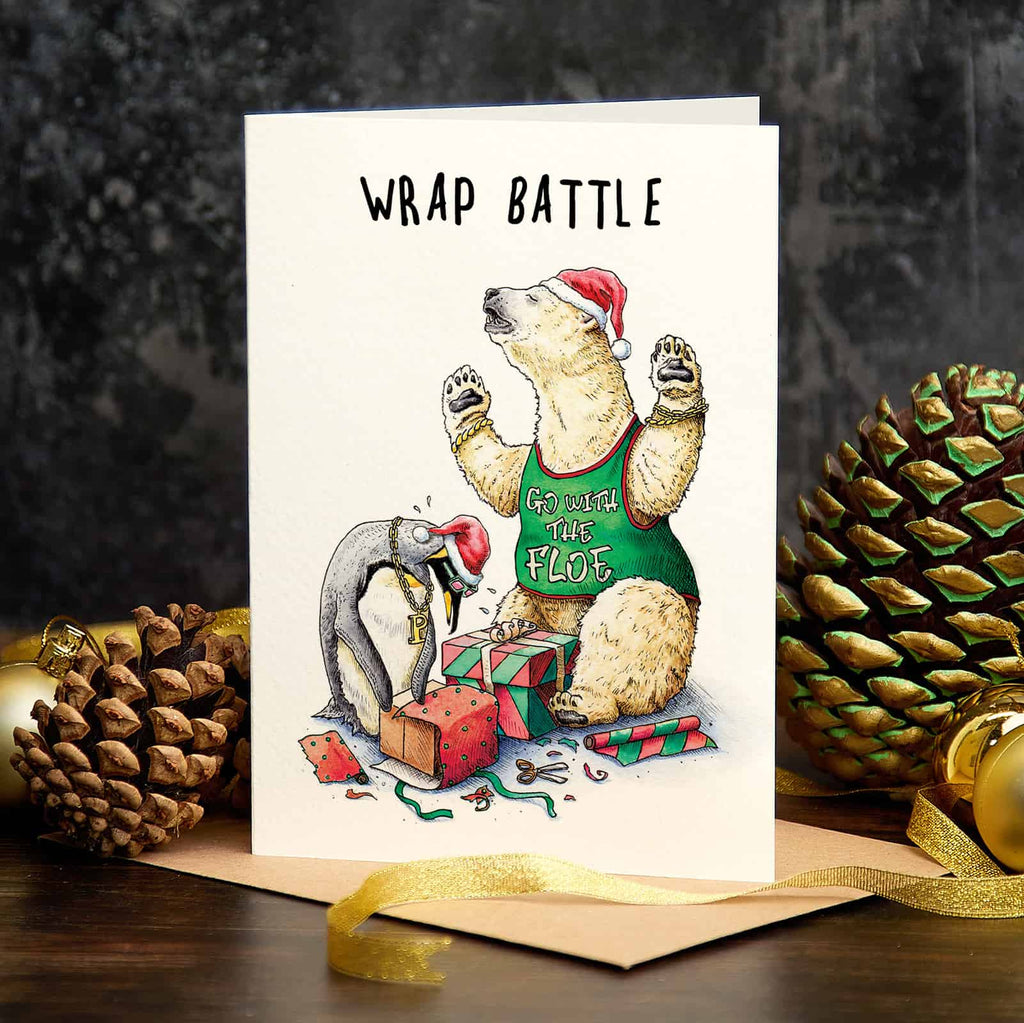 Christmas card with a polar bear and penguin illustration and 'Wrap Battle' text, surrounded by pine cones and ribbons.