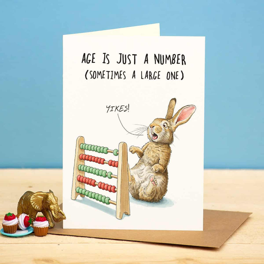 Greeting card with a rabbit and abacus illustration and humorous text on a blue background.
