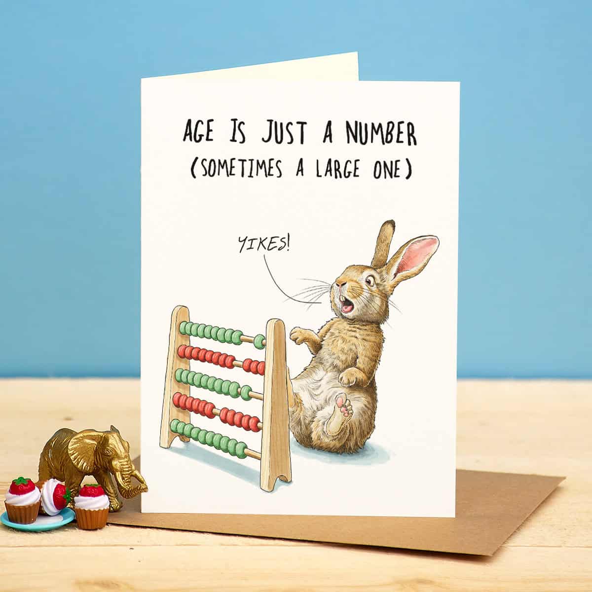 Greeting card with a rabbit and abacus illustration and humorous text on a blue background.