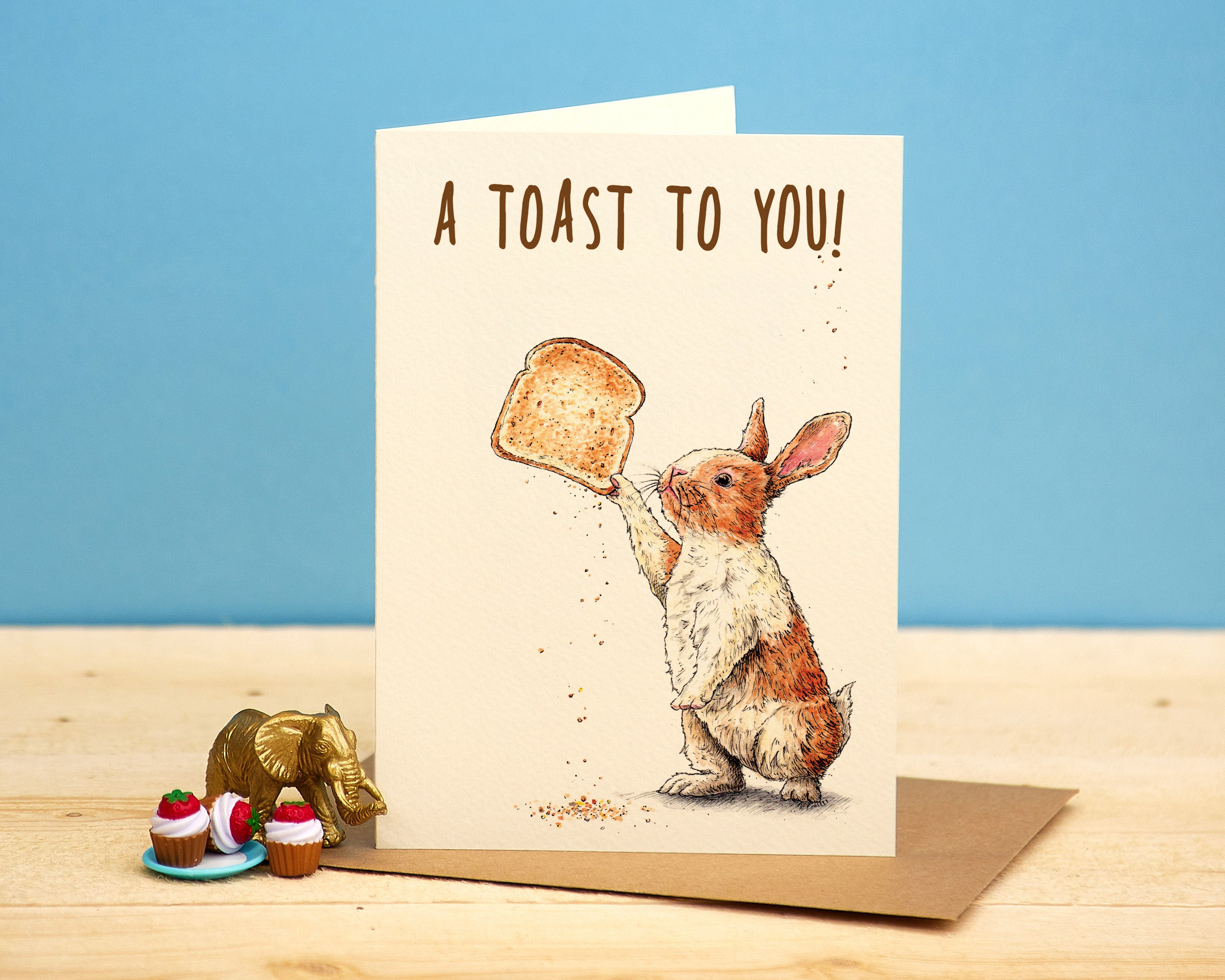 Greeting card with a rabbit holding a toast and 'A Toast to You!' text on a blue background.
