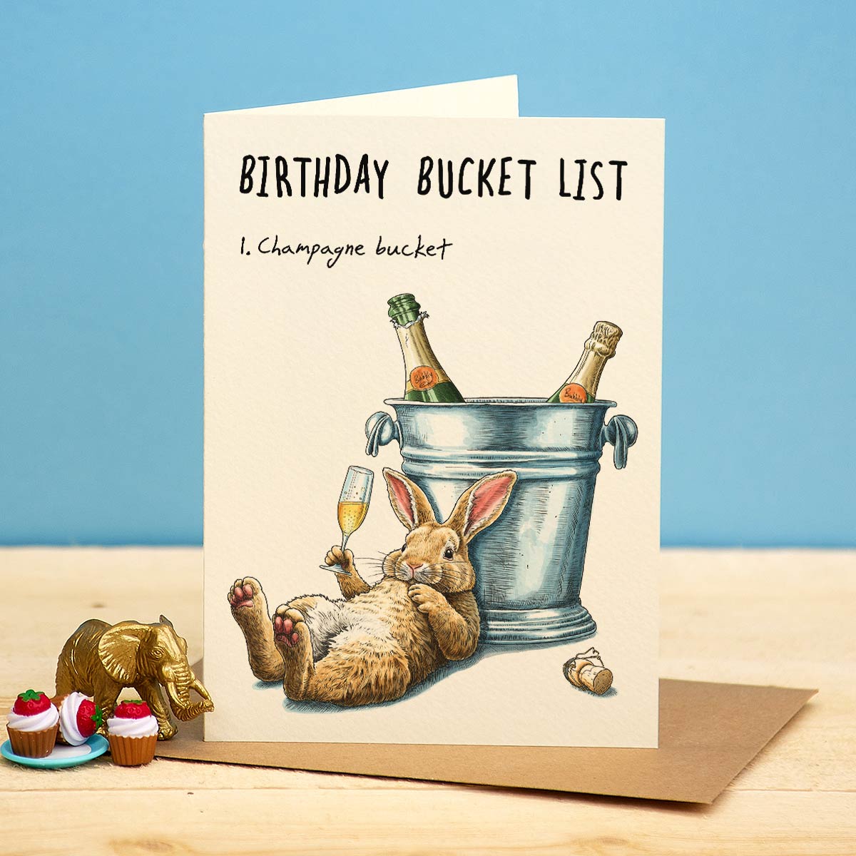 Birthday card with a rabbit and champagne bucket illustration on a blue background