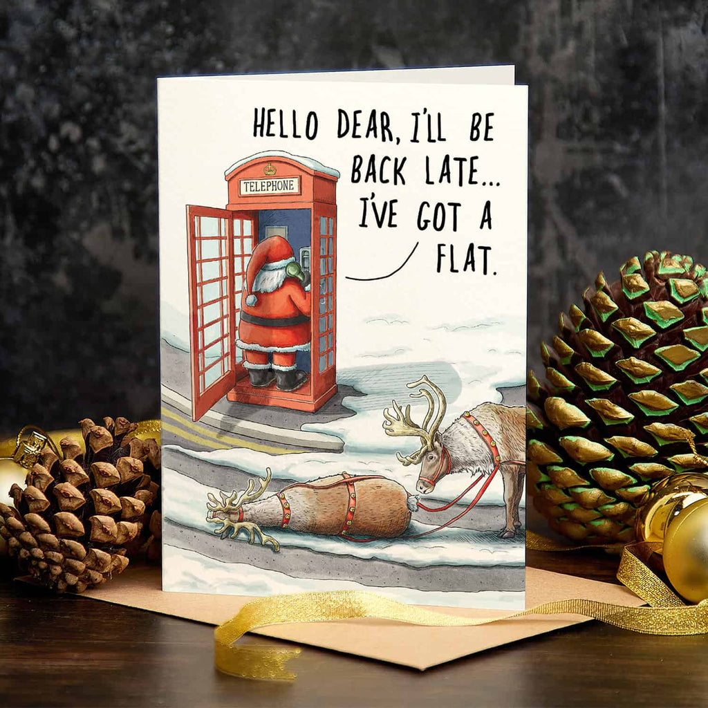Christmas card with Santa in a phone booth and reindeer, surrounded by pine cones and gold ribbons.