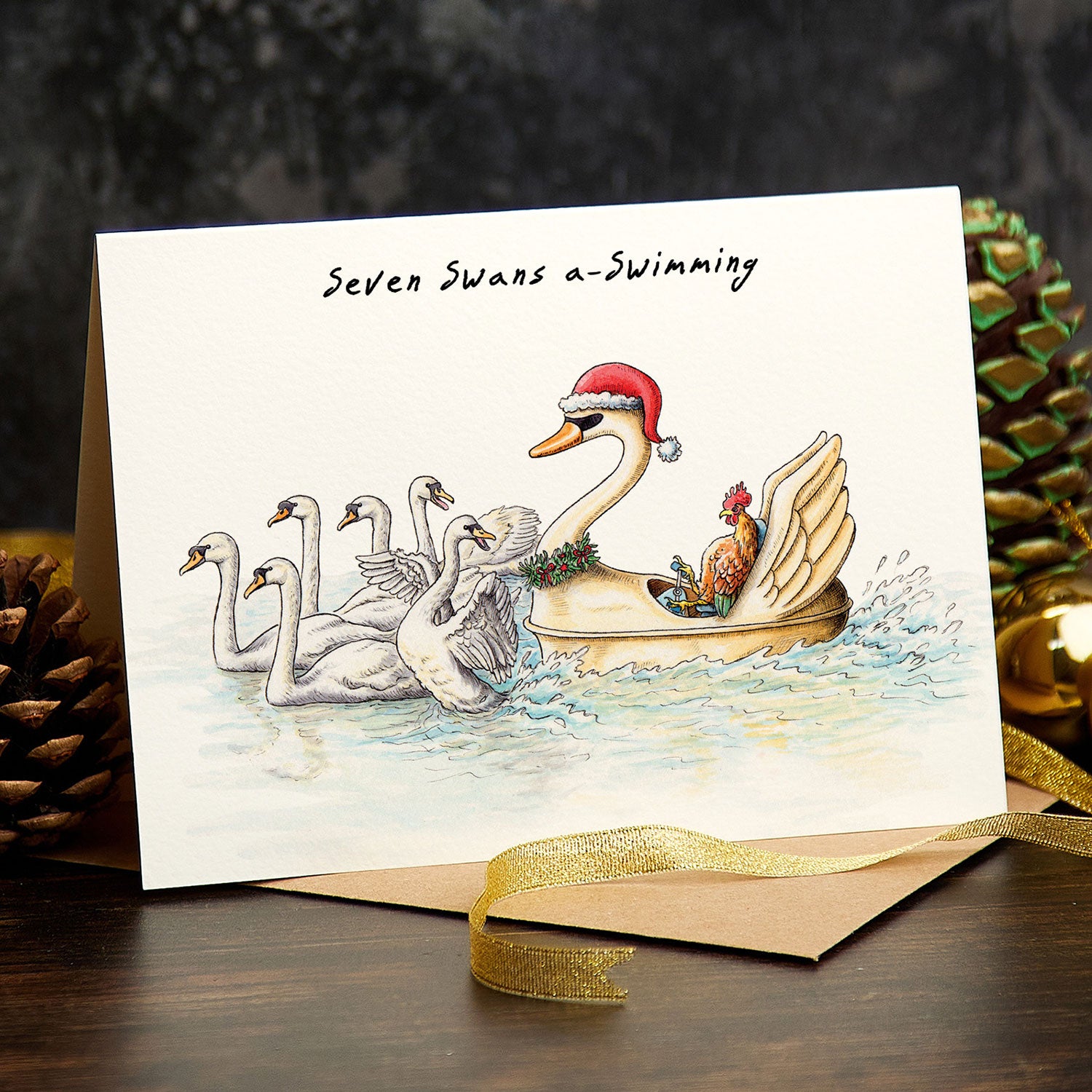 Christmas card with swans and a Santa-clad swan in a boat, surrounded by festive decorations.