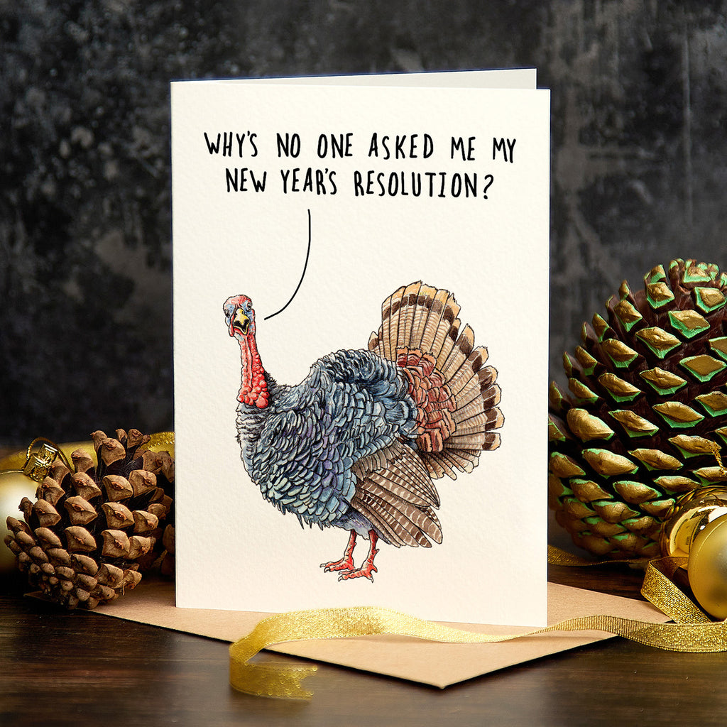 Card with a turkey illustration and humorous text, surrounded by pine cones and a gold ribbon on a dark background.