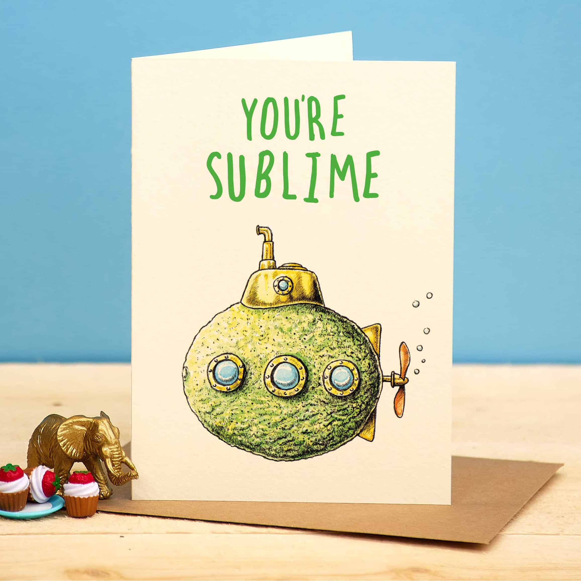Greeting card with a submarine illustration and 'You're Sublime' text on a wooden surface with a blue background.