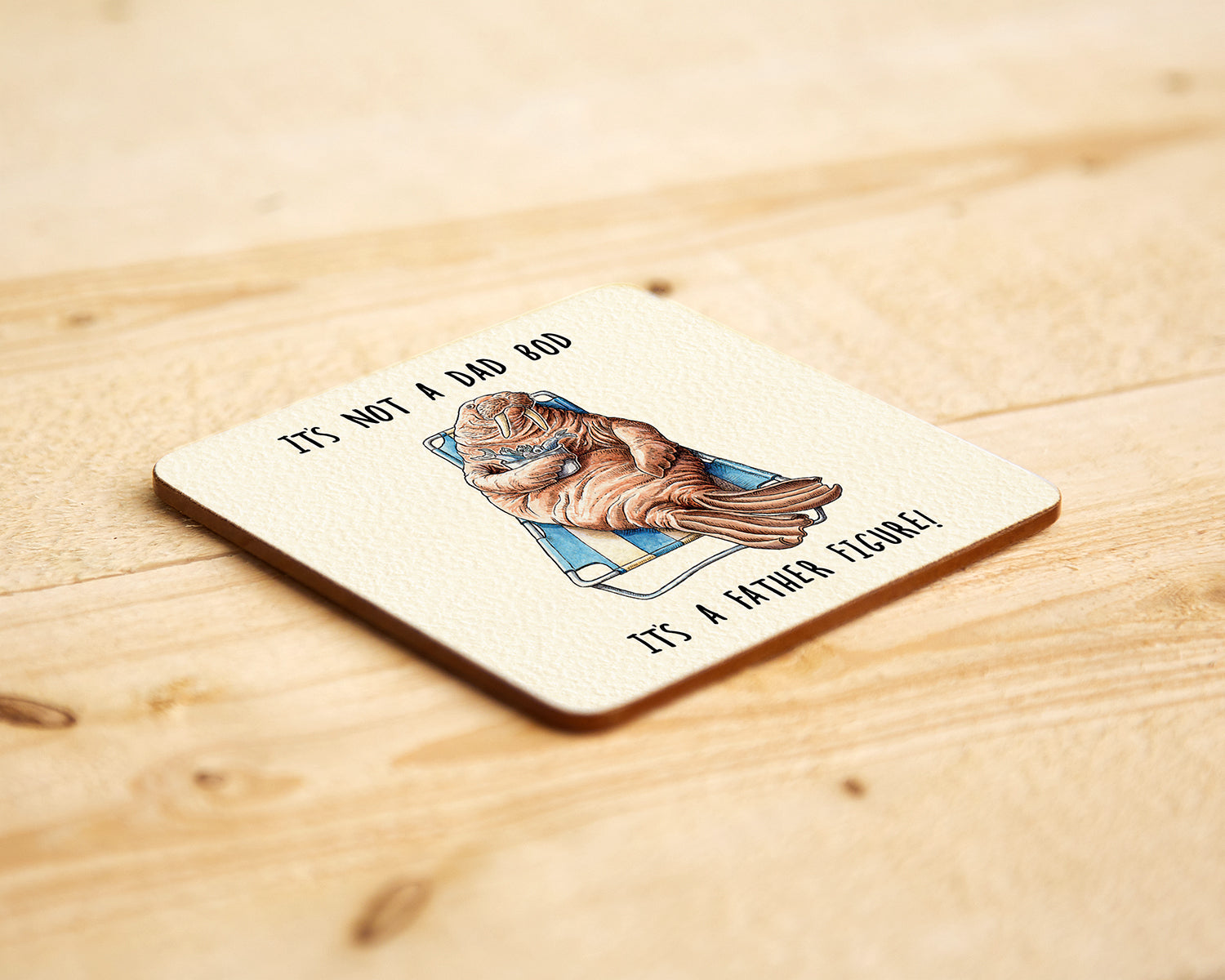 Coaster with a walrus illustration and humorous text on a wooden surface
