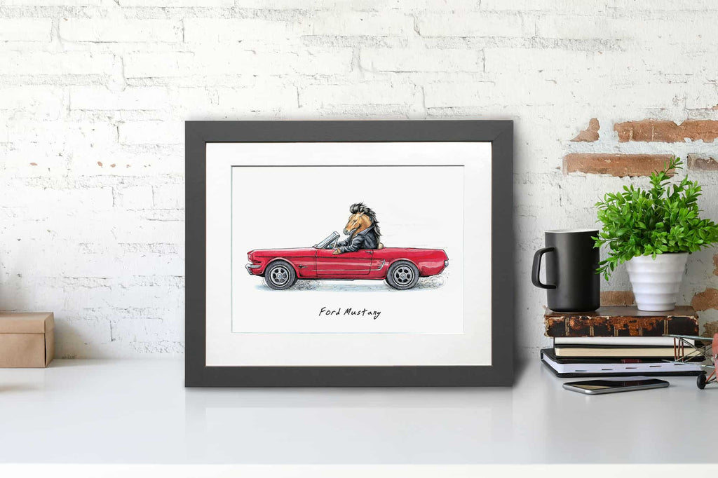Print of a Mustang horse wearing a leather jacket driving a red ford mustang car in a grey frame sitting on a desk