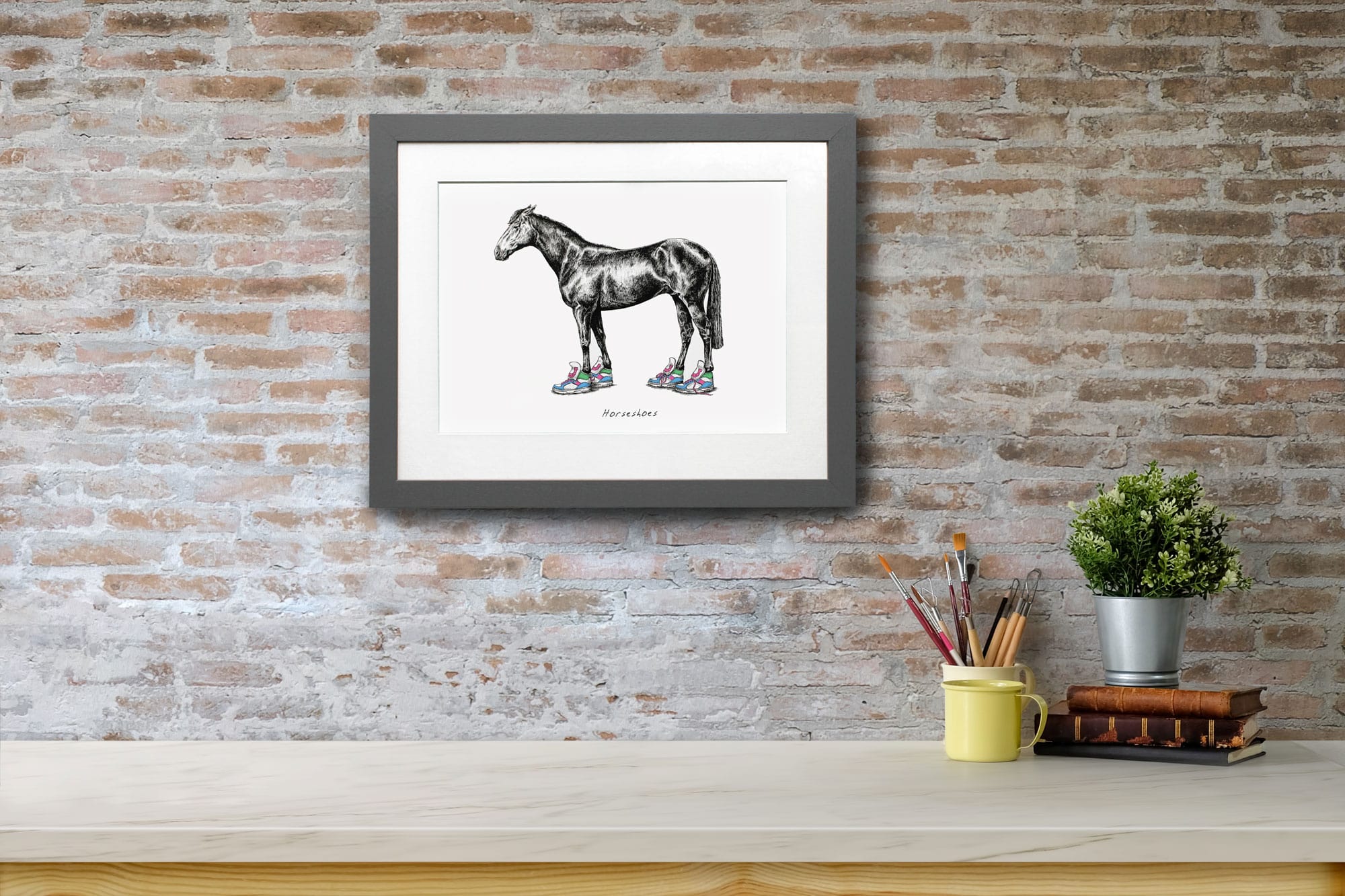 Print of a horse wearing bright coloured trainers in a grey frame on a red brick wall above a white shelf
