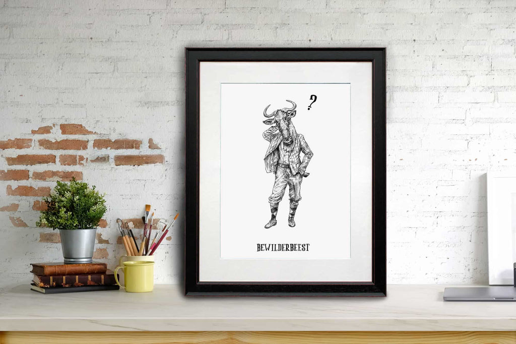 Print of a wildebeest dressed in human clothing in a black frame sitting on a shelf learning against a white brick wall