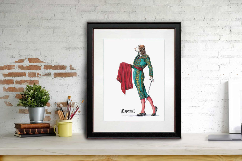 Print of a liver and white Spaniel wearing a traditional Spanish matador outfit in a black frame on a white desk