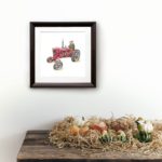 Print of a pig driving a red tractor in a dark wood frame on a white wall above a wooden shelf covered in vegetables