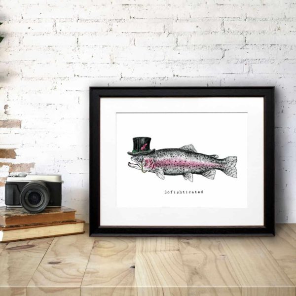 Print of a fish wearing a top hat with a monocle in a black frame on a wooden desk leaning against a white brick wall