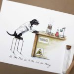 Print of a black labrador wearing a white Lab coat sitting at a desk in a science lab cooking sausages over a Bunsen burner