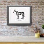Print of a horse wearing bright coloured trainers in a grey frame on a red brick wall above a white shelf