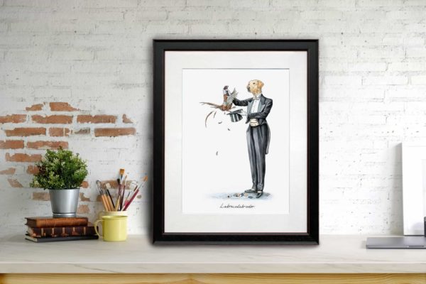 Print of a Yellow Labrador in a magician’s outfit pulling a pheasant out a hat in a black frame leaning against a brick wall